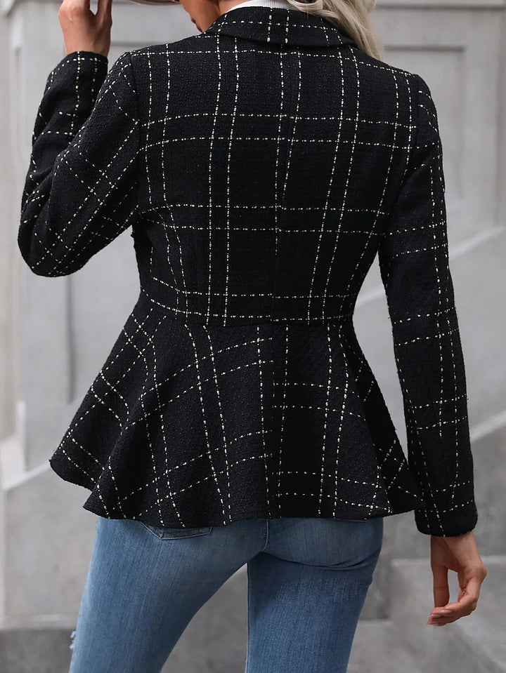 Back view of woman wearing black plaid peplum blazer paired with blue jeans in urban setting