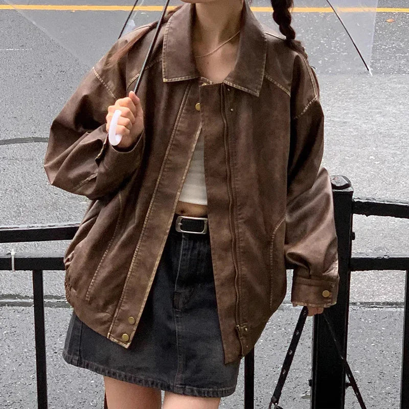 Person wearing oversized brown leather jacket and black denim skirt holding transparent umbrella