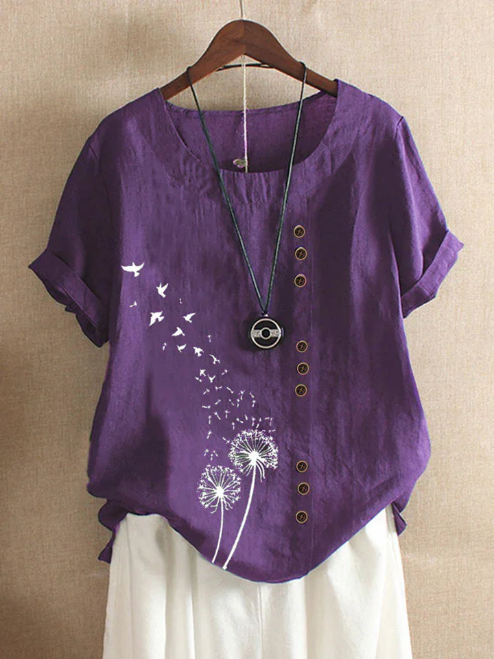 Purple linen short-sleeve blouse with white dandelion and bird print, wooden buttons, and black pendant necklace