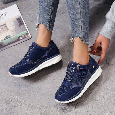 Navy blue casual sneakers with white soles worn with frayed hem jeans on a gray floor