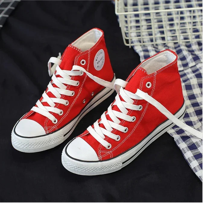 Pair of red high-top canvas sneakers with white laces and rubber soles on black and checkered cloth