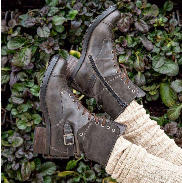 Dark brown leather lace-up ankle boots with side zipper and buckle, worn with beige knit socks against leafy background