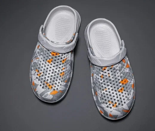 White and orange patterned slip-on shoes with perforated upper and adjustable straps on gray background