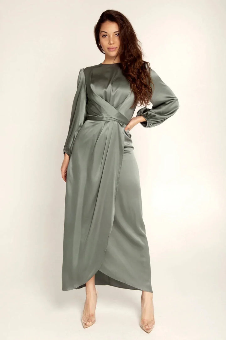 Woman wearing elegant long-sleeve sage green satin wrap dress and clear high heels