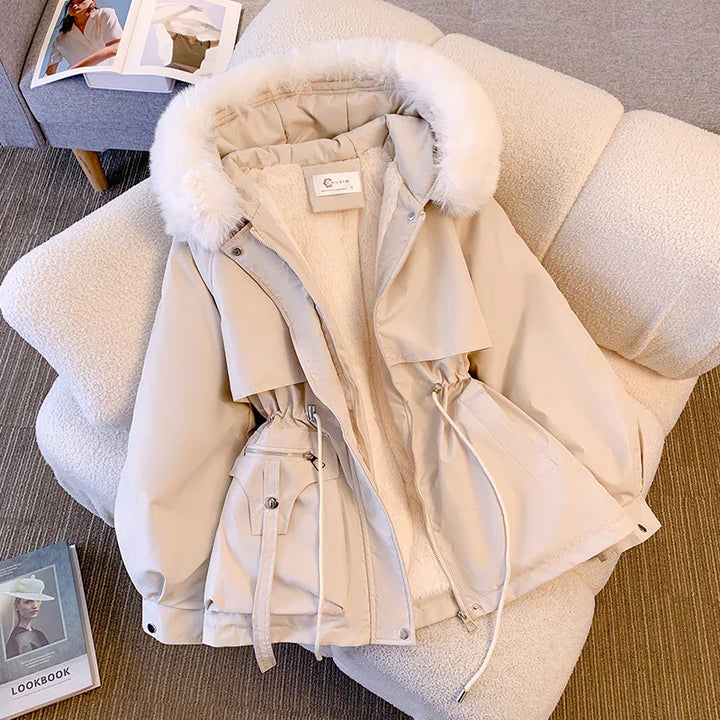 Beige winter parka with white fur hood and inner fleece lining displayed on cream textured chair