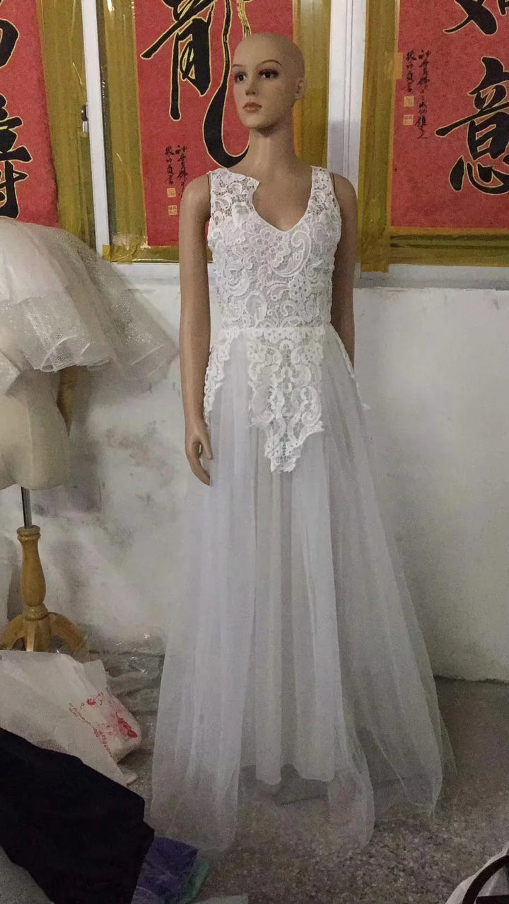 Mannequin wearing a white lace sleeveless gown with a long tulle skirt in a room with Asian calligraphy art