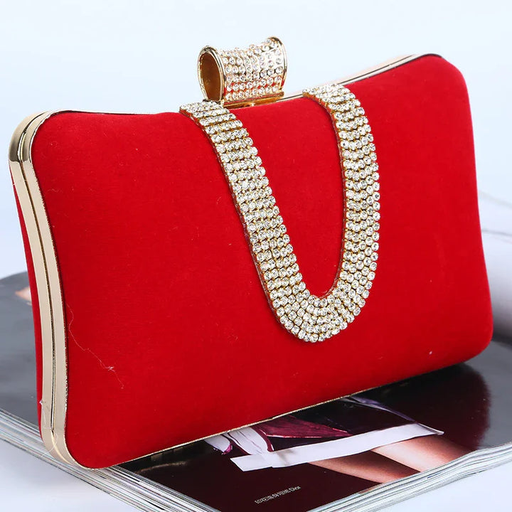 Red velvet evening clutch bag with gold trim and rhinestone chain strap on magazine