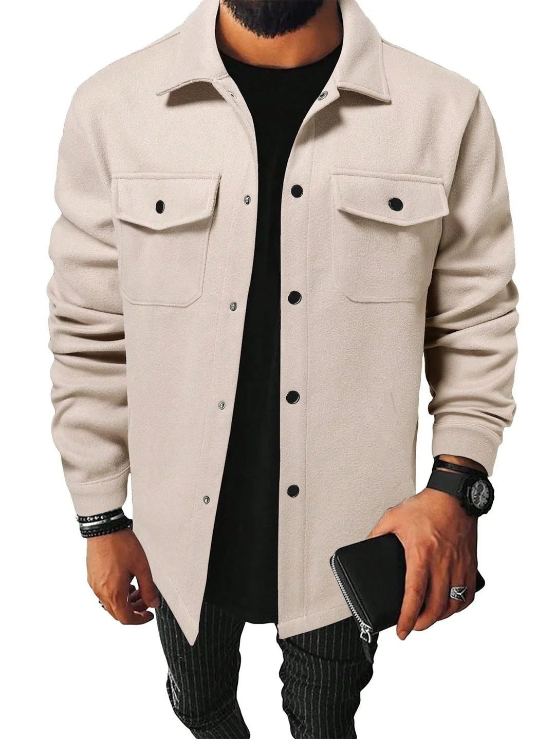 Man wearing beige button-up shirt jacket with flap pockets over black shirt and holding black wallet