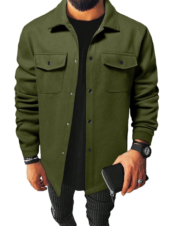 Man wearing olive green button-up jacket with chest pockets, black shirt, striped pants, and accessories
