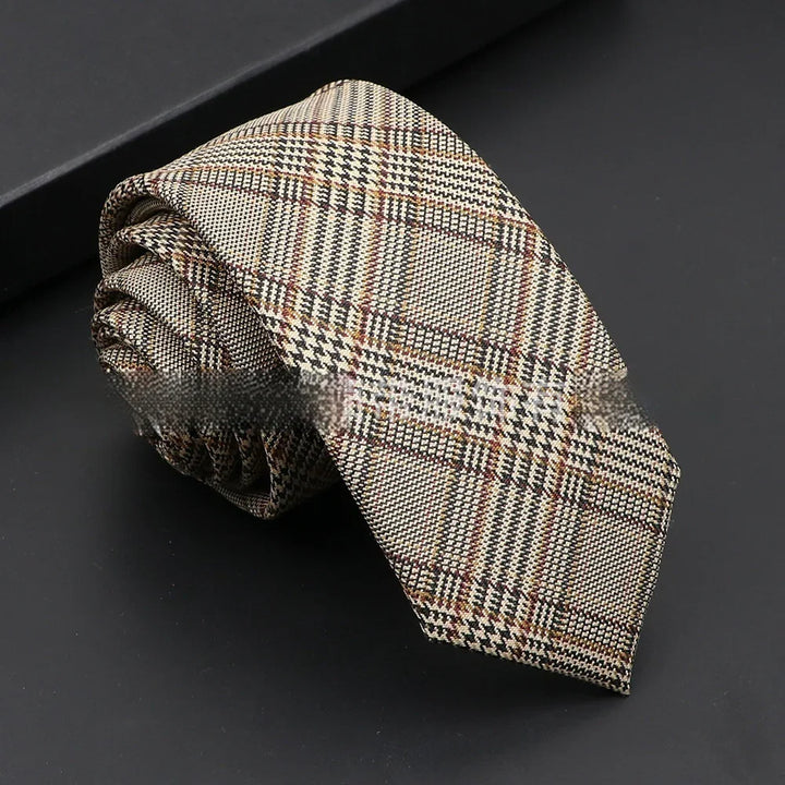 Rolled beige plaid men's necktie with black and brown checks on black surface
