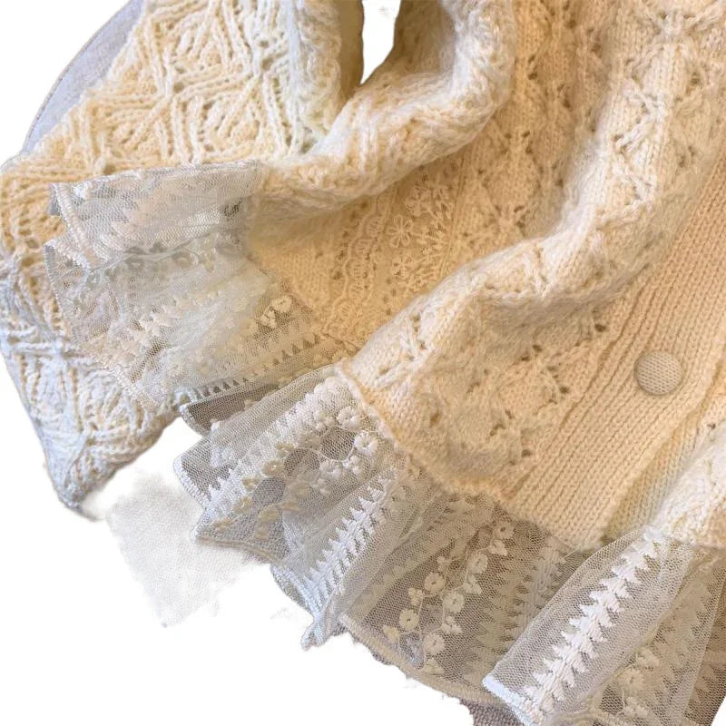 Cream knit sweater with intricate cable patterns and delicate white lace ruffle trim on cuffs