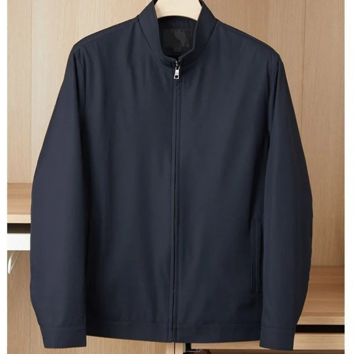 Navy blue zip-up casual jacket with stand collar hanging on wooden hanger against beige background
