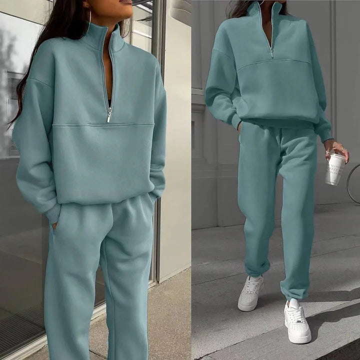 Two views of a woman wearing a light blue zip-up sweatshirt and matching jogger pants with white sneakers