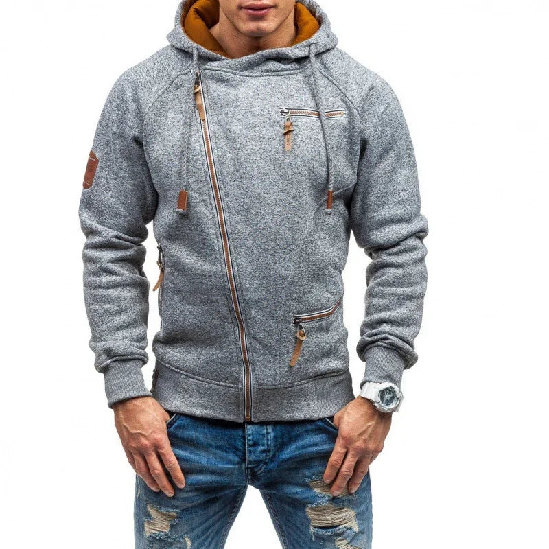 Man wearing gray zip-up hoodie with asymmetric zipper and brown leather accents, paired with ripped blue jeans