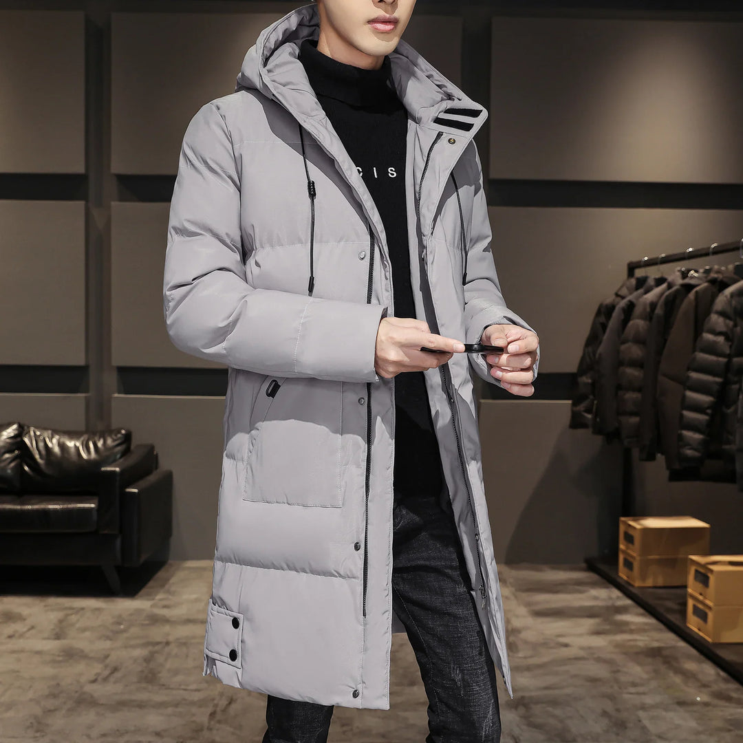 Man wearing a long light gray puffer jacket with hood in a modern retail store