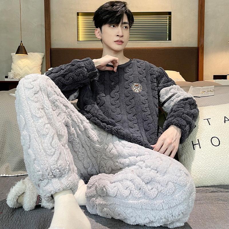 Young man wearing black and gray cozy cable knit fleece loungewear sitting on bed in modern bedroom