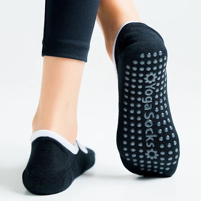 Black yoga socks with white trim and anti-slip grips on soles worn with black leggings