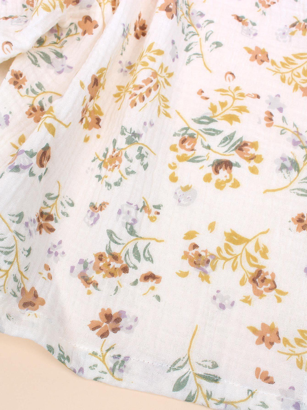 White fabric with delicate floral print in mustard, brown, green, and light purple colors