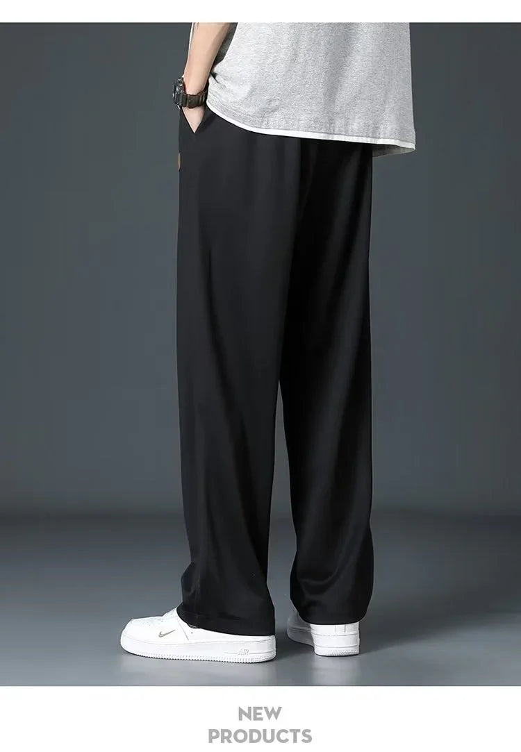Person wearing black wide-leg pants, white sneakers, and gray t-shirt against gray background
