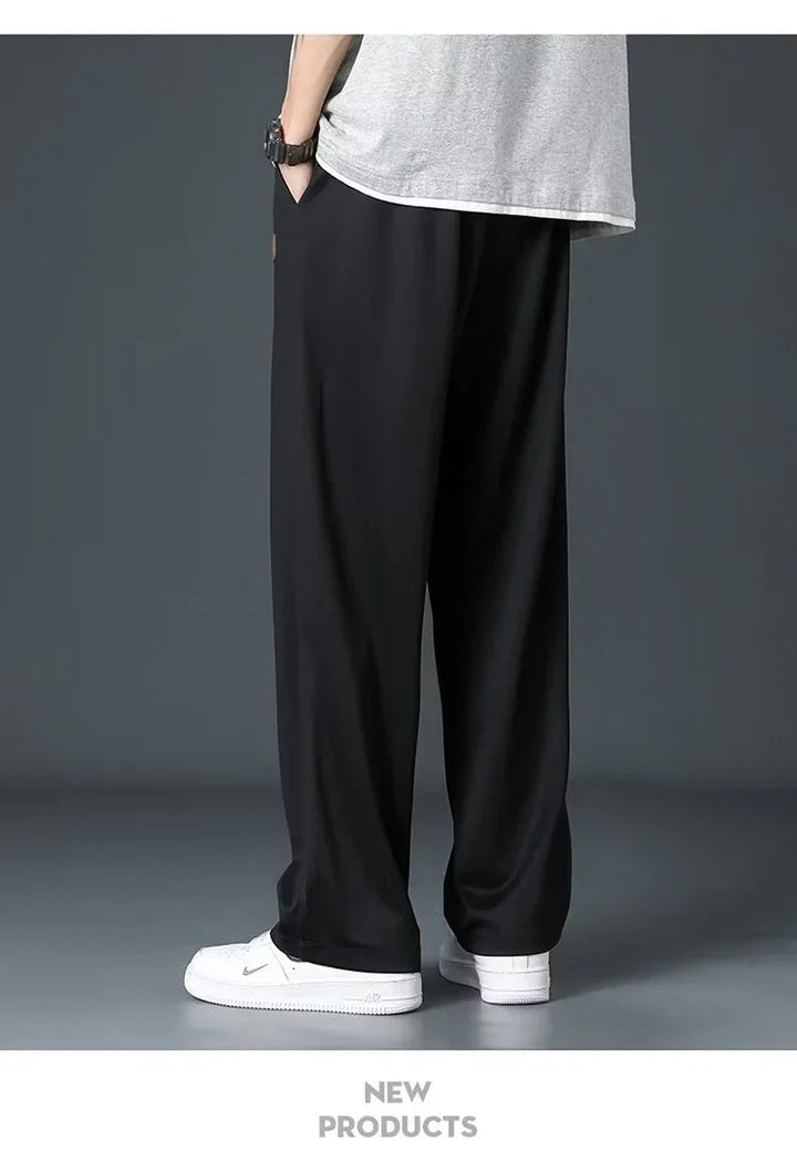 Person wearing black wide-leg pants, white sneakers, and gray t-shirt against gray background
