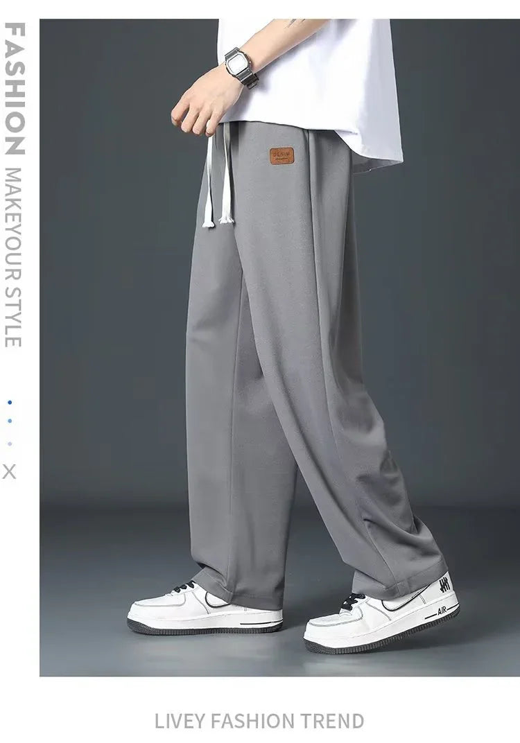 Casual gray wide-leg pants with drawstring worn by model with white sneakers on gray background