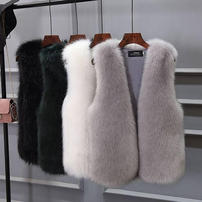 Luxury faux fur vests in black, dark green, white, and gray hanging on wooden hangers against gray wall
