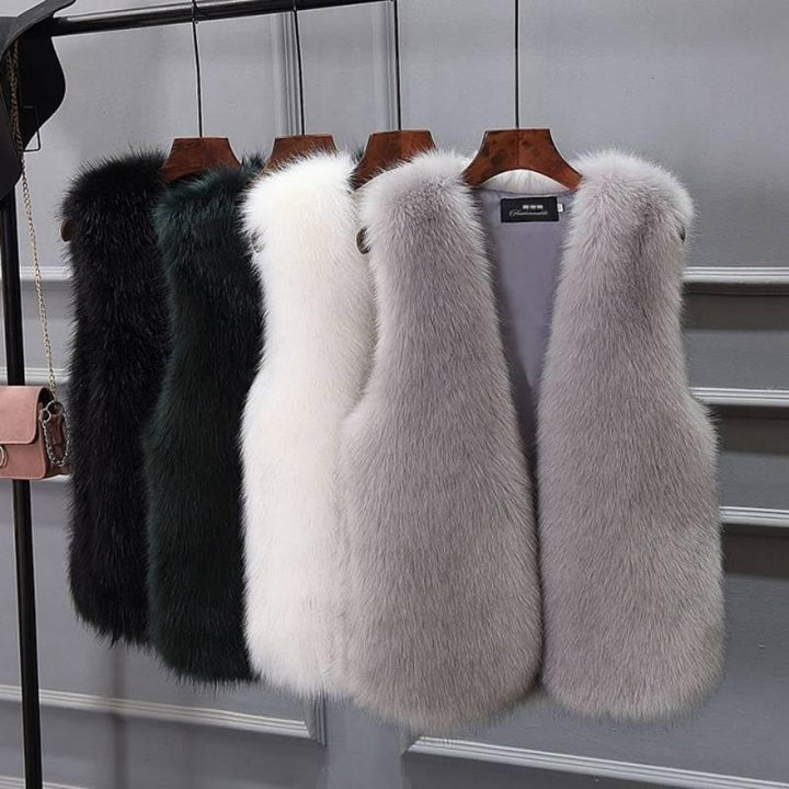 Luxury faux fur vests in black, dark green, white, and gray hanging on wooden hangers against gray wall