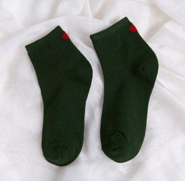 Pair of dark green ankle socks with small red heart detail on white fabric background