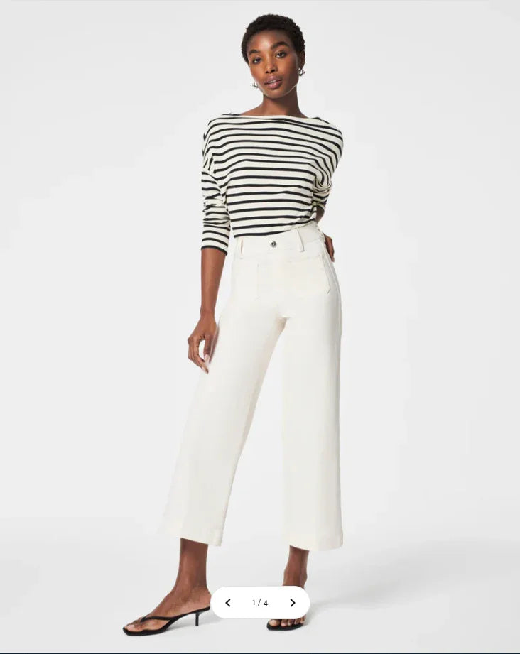 Woman wearing black and white striped long-sleeve top, white wide-leg cropped pants, and black heeled sandals