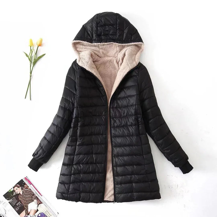 Black quilted winter coat with beige fleece lining and hood on white background with yellow flowers and magazine