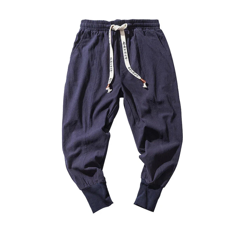 Navy blue casual jogger pants with elastic waistband and white drawstring featuring black text