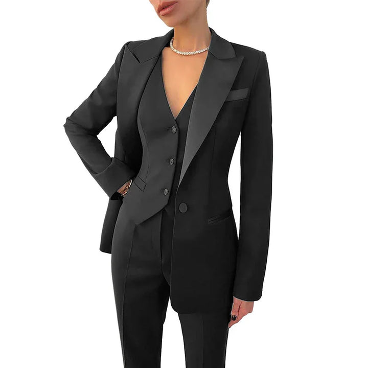 woman wearing a tailored black suit with blazer, vest, and trousers, accessorized with a pearl necklace