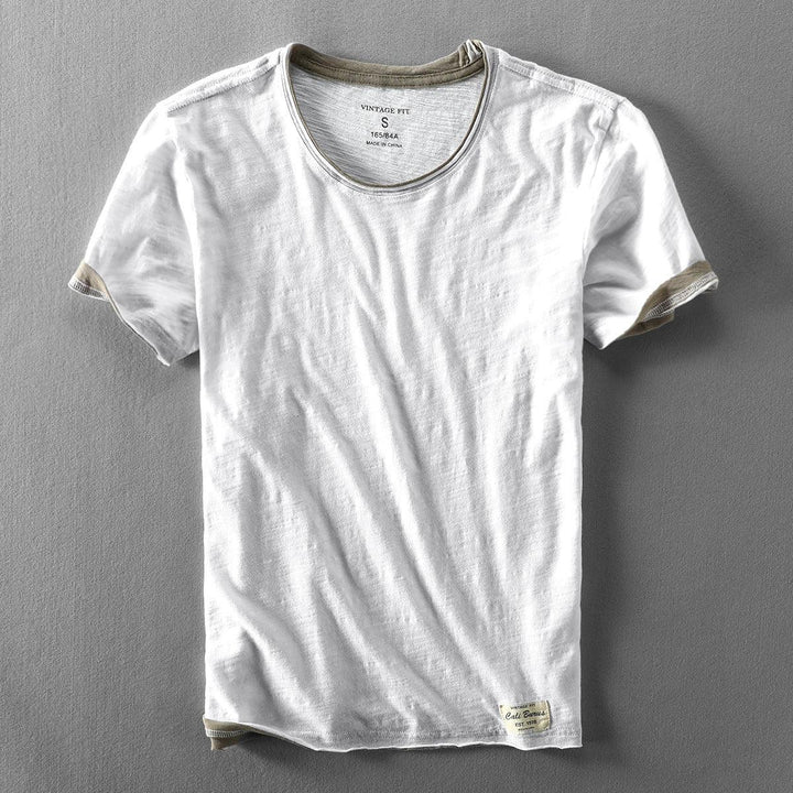 white vintage fit short sleeve t-shirt with beige trim on collar and cuffs, laid flat on gray surface