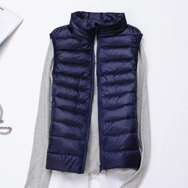 Navy blue quilted puffer vest layered over a light gray long sleeve shirt on white background