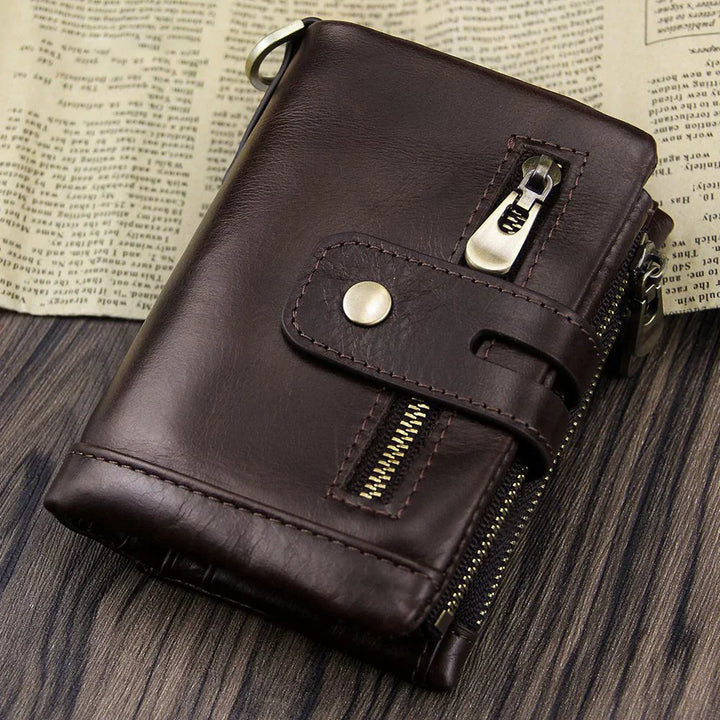 Dark brown leather wallet with zipper and snap button closure on wooden surface