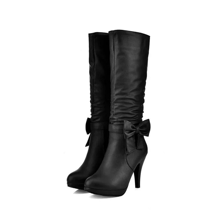 Black high-heeled knee boots with decorative bow detail on side, sleek leather texture