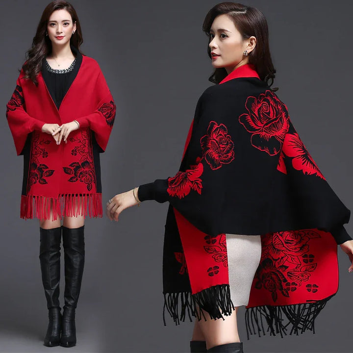 Woman wearing red and black floral patterned fringed shawl with black over-the-knee boots on gray background