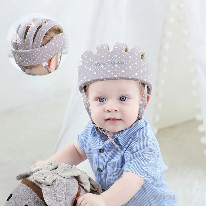 Baby wearing padded star-patterned helmet playing with stuffed animal in bright room