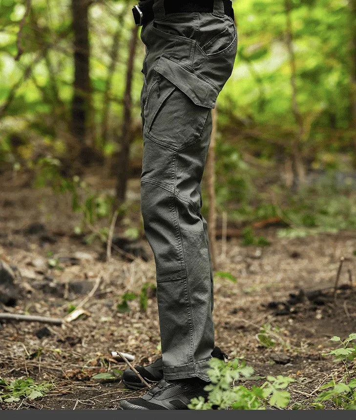 Side view of person wearing gray tactical cargo pants and black shoes in a forest setting