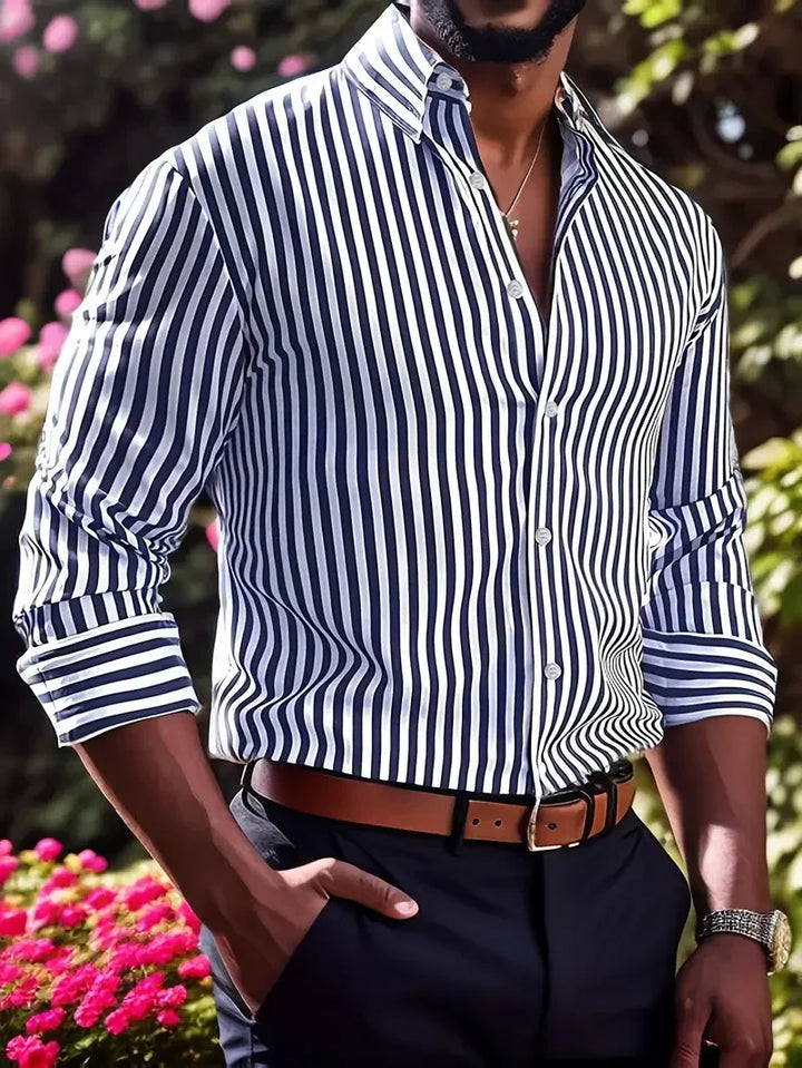 Man wearing blue and white vertical striped dress shirt with rolled sleeves, brown belt, and dark pants outdoors
