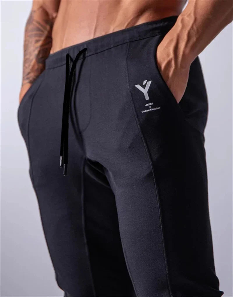 Close-up of muscular man wearing black jogger pants with pockets and logo detailing