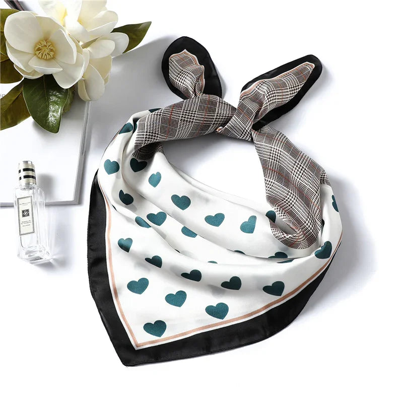 Silk scarf with teal hearts and plaid pattern, styled with white magnolia flowers and perfume bottle
