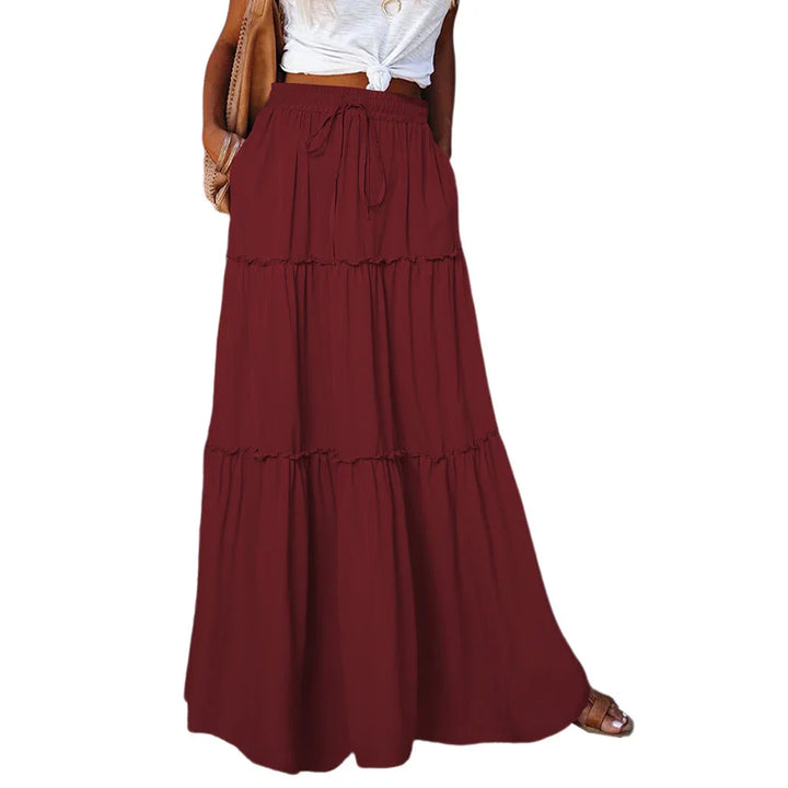 Woman wearing a long burgundy tiered maxi skirt with drawstring waist and pockets