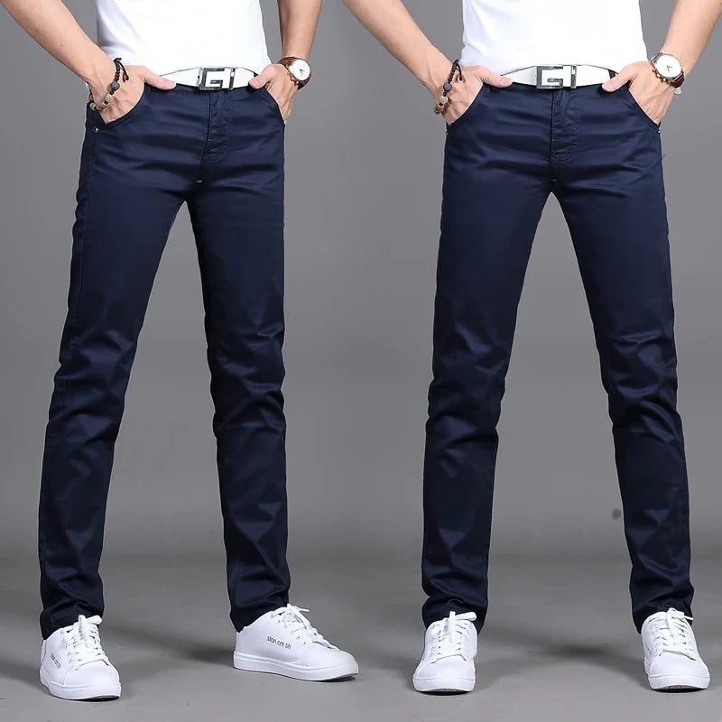 Front view of man wearing slim fit navy blue pants with white belt, white sneakers, and white shirt