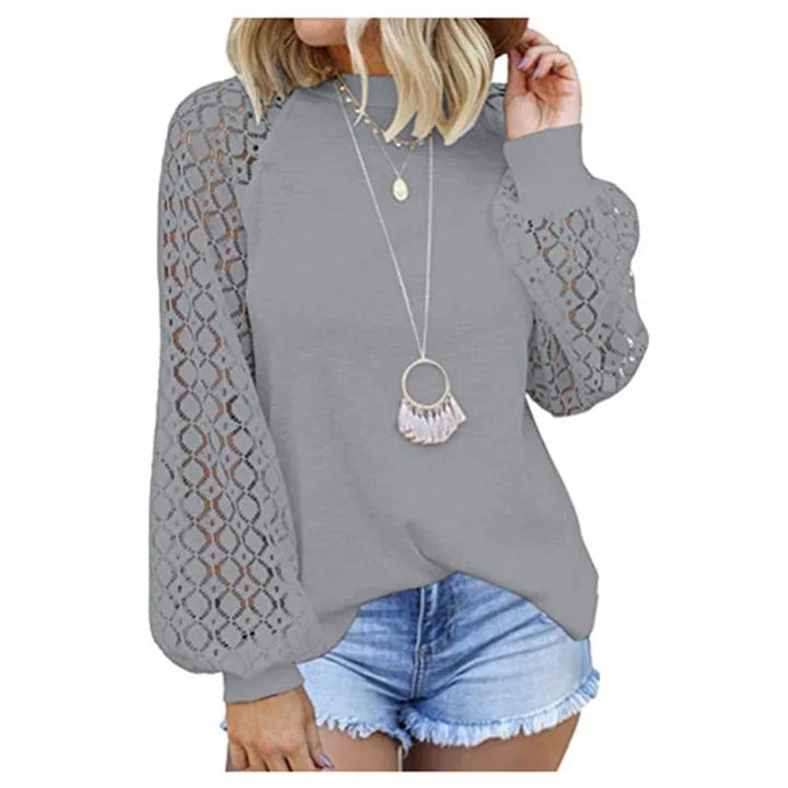 woman wearing gray lace sleeve blouse with long necklace and denim shorts on white background