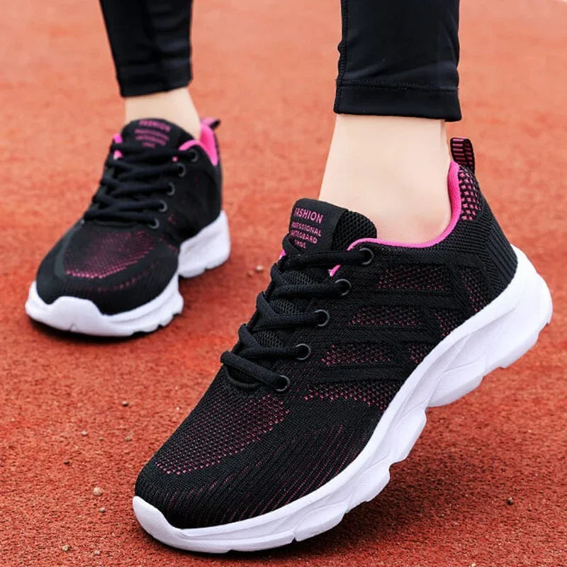 Black and pink breathable running shoes with white soles worn on red track surface