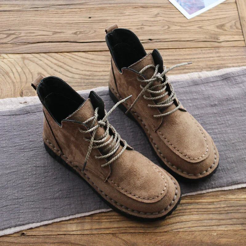 Brown suede lace-up ankle boots on gray fabric and wooden floor, casual men's footwear