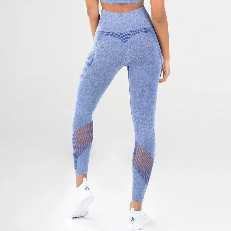 Woman wearing blue seamless high-waisted leggings with mesh panels and white sneakers on a plain background