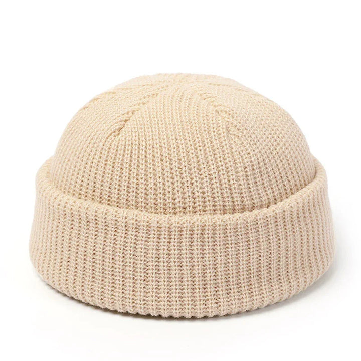 Beige knitted wool watch cap with folded cuff on white background