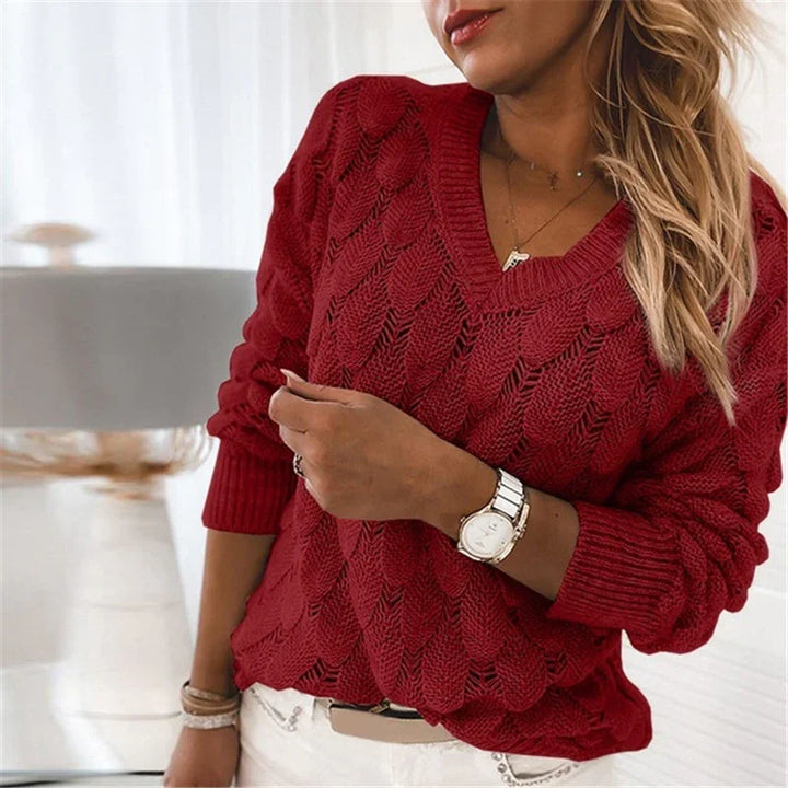 Woman wearing a red cable knit V-neck sweater with long sleeves and white pants